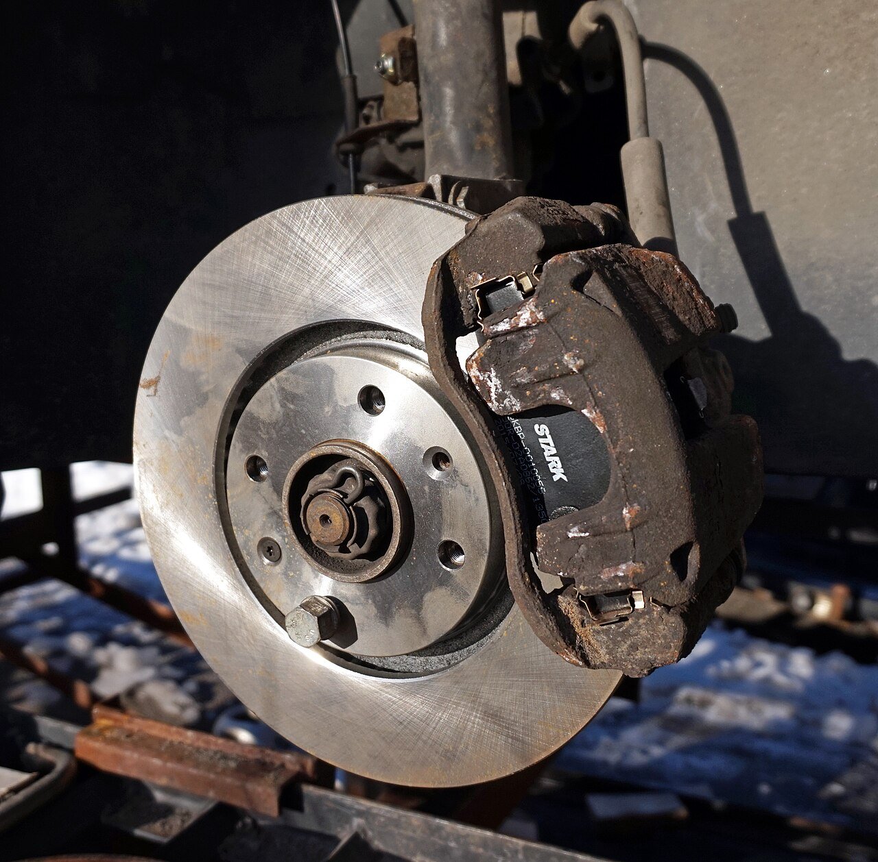 Brake pad visible inside a caliper beside a brake disc