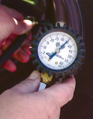 Person using a tire pressure gauge at a wheel valve